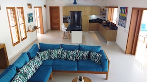 Uma sala moderna com sofá seccional, cozinha com armários de madeira e área de jantar.