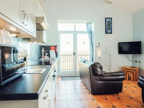 Cocina compacta con comedor, sofá y televisor.