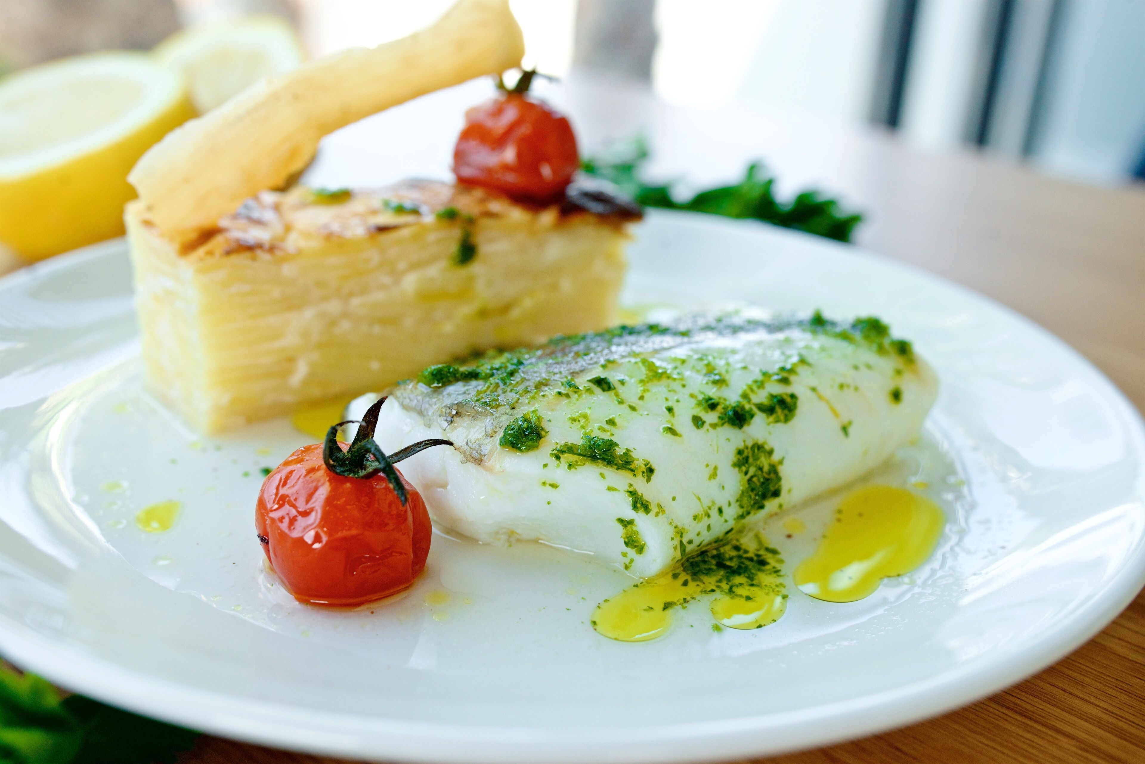 A plate with fish, cherry tomatoes, and a piece of bread.