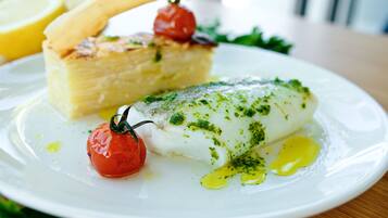 A plate with fish, cherry tomatoes, and a piece of bread.
