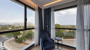 A modern room with a large window, a dark armchair, and a small table. - Syncrosfera Fitness & Spa Health Hotel Boutique (Pedreguer)