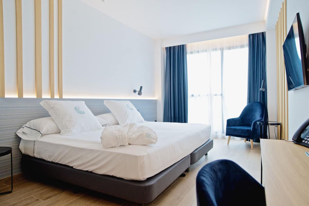 Une chambre d’hôtel moderne équipée d’un grand lit, d’un bureau, d’une chaise et d’un téléviseur.