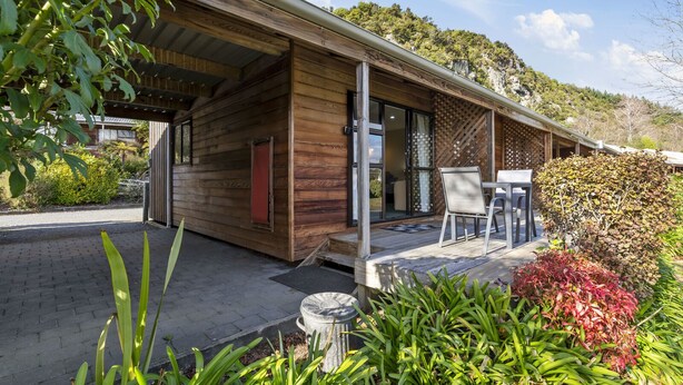 Une cabane en bois dotée d’un patio couvert, d’un coin repas avec des chaises et offrant une vue sur un paysage montagneux.