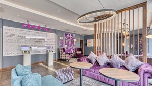 Eine moderne Hotelhalle mit Empfangstresen, Sitzgelegenheiten und Dekorationselementen.