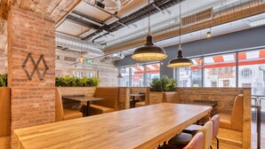 Ein modernes Restaurant mit Ziegelwänden, Holztischen und Sitzecken.