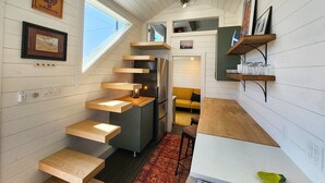 A compact kitchen with built-in appliances, wooden shelves, and a small dining area. - Big Stump (Lincoln County)