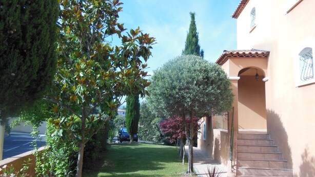 A residential area with a well-maintained lawn, a tall tree, and a building with a tiled roof and a staircase leading to the entrance. - Independent 25m2 studio in Villa: Wi-fi + terrace (Saint-Gély-du-Fesc)