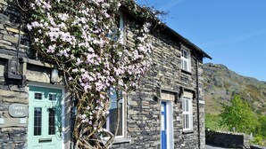 Ein Steinhaus mit einer grünen Tür mit der Aufschrift 'Carrie's Gate', einer blauen Tür und einer Steintreppe, die zum Eingang führt.