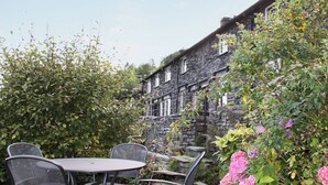 Ein Steinhaus mit Garten-Terrasse, komplett mit Tisch und Stühlen.