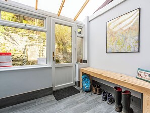 A room with a wooden bench, a map on the wall, and a door leading outside. - 2 bedroom accommodation in Coniston (Coniston)