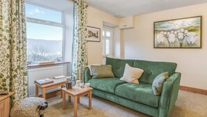 A cozy living room with a green sofa, a wooden coffee table, and a small table with a kettle and cups. - 2 bedroom accommodation in Coniston (Coniston)