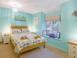 A bedroom with a bed, bedside tables, a window with a view, and a chandelier.
