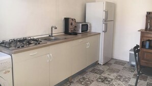 Una cocina compacta equipada con estufa a gas, pileta, microondas y refrigerador.