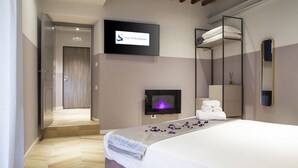A modern hotel room with a bed, a TV mounted on the wall, a fireplace, and a mirror. - Colle di Val d'Elsa - Siena - Apt Pink - B (Colle di Val d'Elsa)