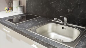 A modern kitchen with a black marble countertop, stainless steel sink, and white cabinetry. - Colle di Val d'Elsa - Siena - Apt Pink - B (Colle di Val d'Elsa)