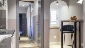 A modern kitchen with a herringbone floor, a dining area with a black chair, and a window with a view. - Colle di Val d'Elsa - Siena - Apt Pink - B (Colle di Val d'Elsa)