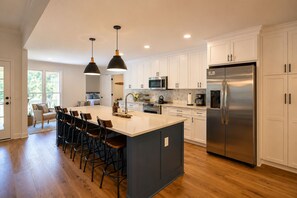A modern kitchen with a central island, stainless steel appliances, and pendant lighting.