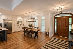 A spacious kitchen with a central island, stainless steel appliances, and a dining area with wooden chairs.