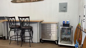 A bar area with two stools, a metal storage unit, and a refrigerated display case.