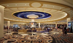 A hotel lobby with a central bar, a patterned floor, and a ceiling with a galaxy-themed design.