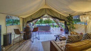 A tented accommodation with a dining area, seating, and a view of the outdoors.