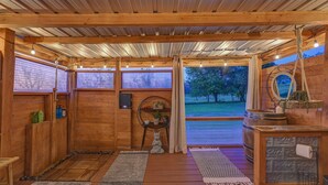 A wooden sauna room with a bench, a small table, and a shelf with bottles.