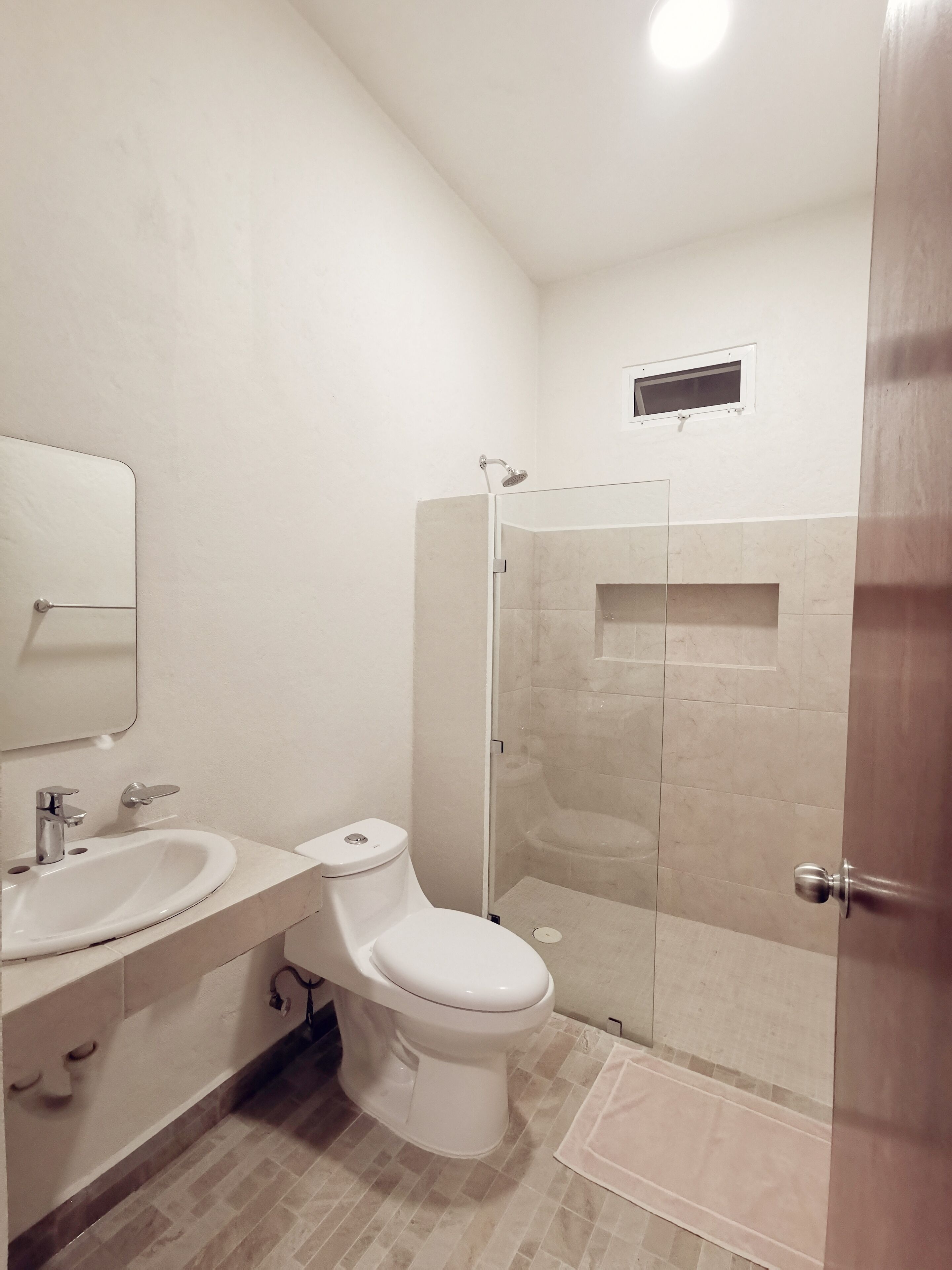 Une salle de bain moderne équipée de toilettes, d’un lavabo et d’une douche à parois de verre.