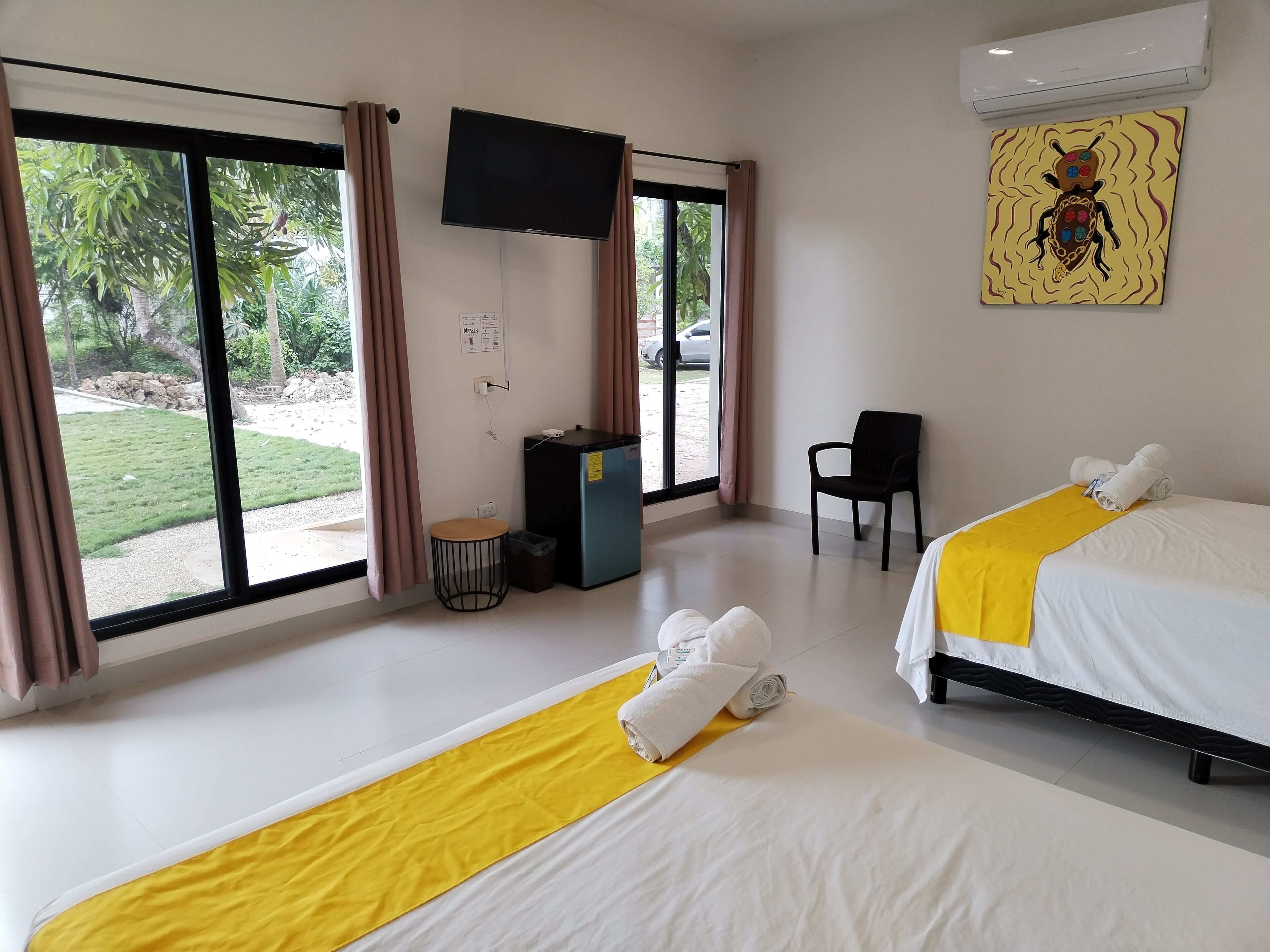 Een hotelkamer met twee bedden, een televisie, een bureau en een stoel.