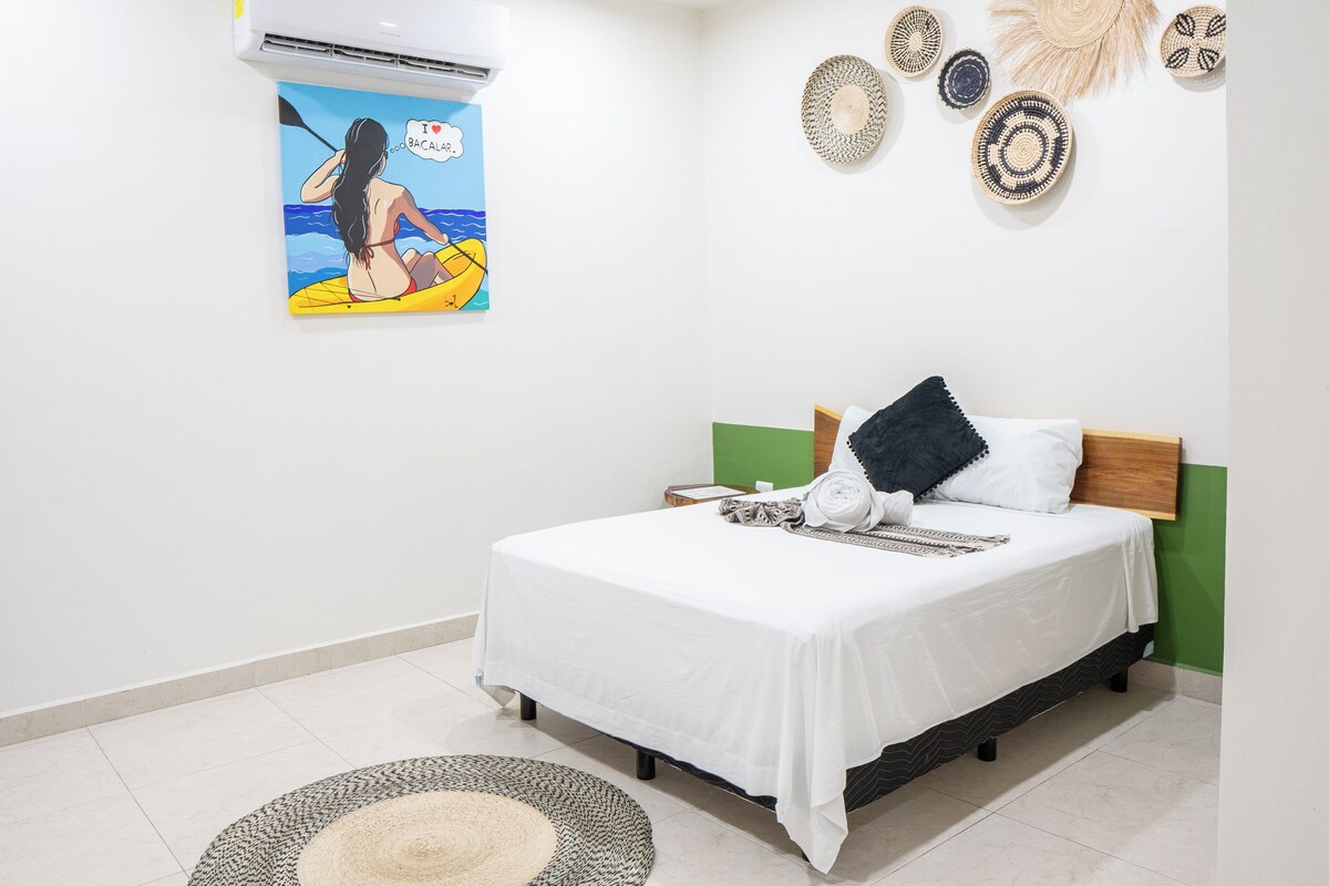 Un dormitorio con una cama, aire acondicionado instalado en la pared, un cuadro y adornos decorativos en la pared.