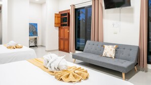 A hotel room with two beds, a sofa, a TV, and a sliding glass door.