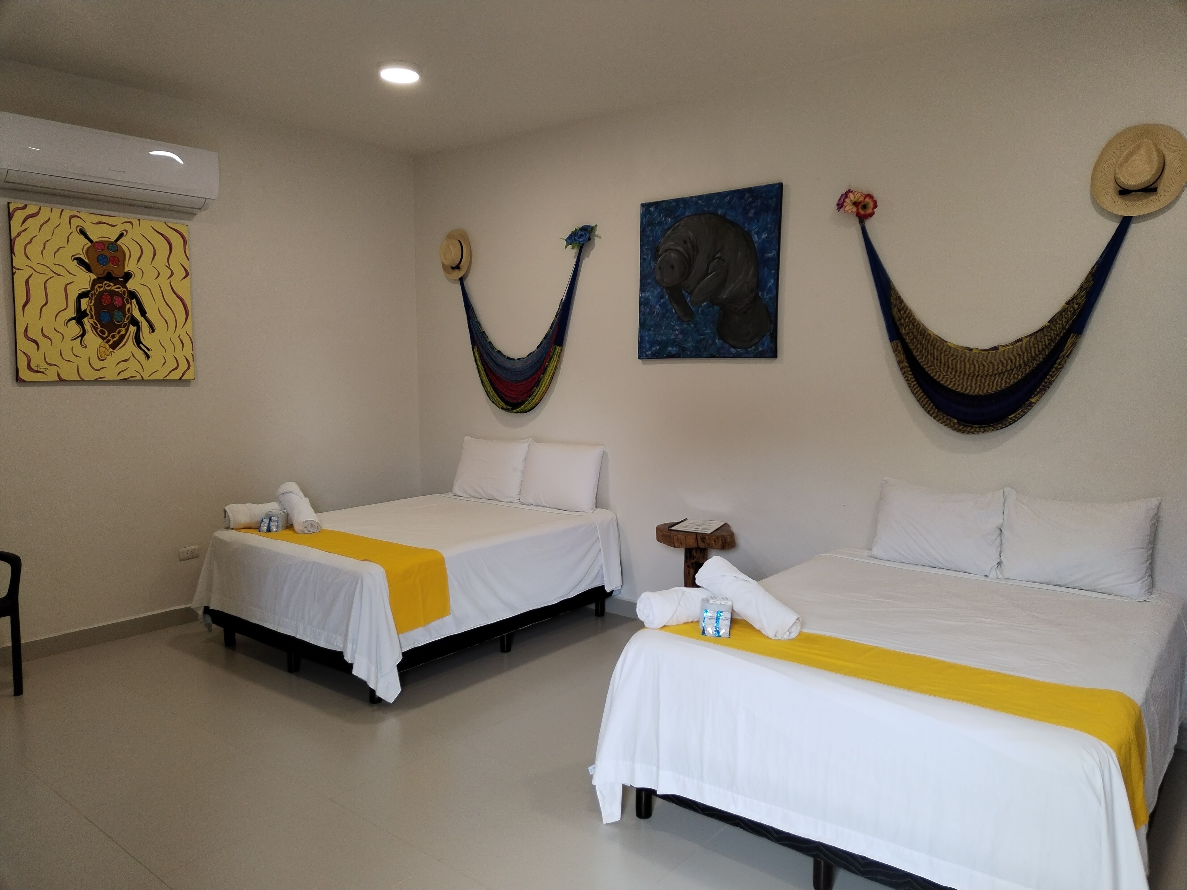 Habitación de hotel con dos camas, una mesita y una hamaca.