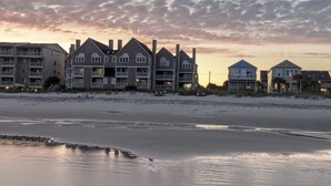 Un hotel frente a la playa con varias edificaciones, incluyendo una estructura grande con balcones y un edificio más pequeño con techo azul.