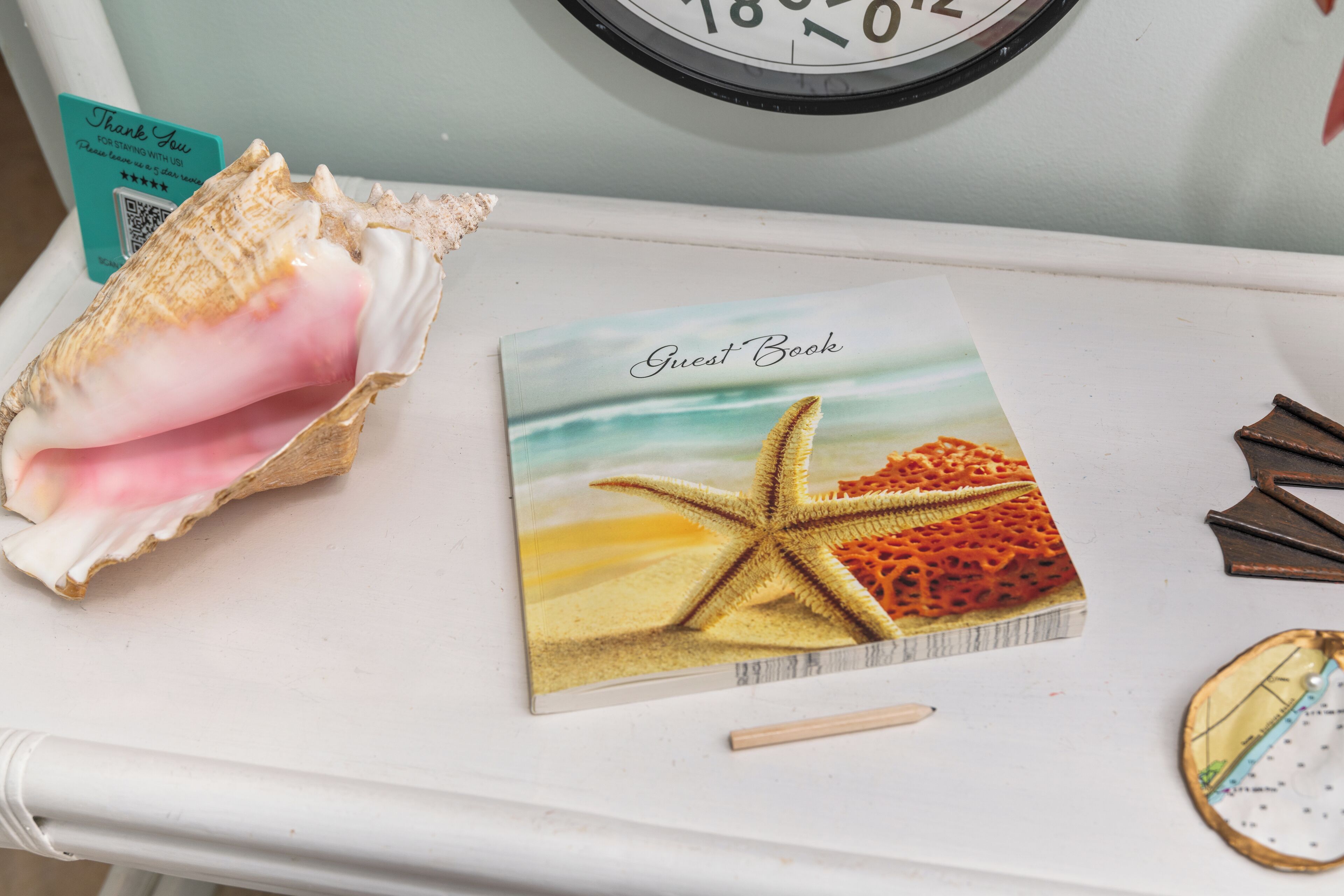 A guest book, a starfish, and a seashell on a white table.