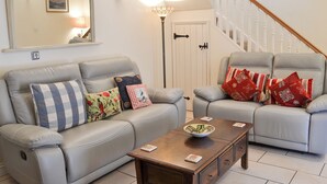 A living room with a sofa, armchairs, a coffee table, a lamp, a mirror, and a staircase. - 3 bedroom accommodation in Seahouses (Seahouses)