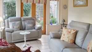 A living room with a grey sofa, a wicker chair, and a small table. - 3 bedroom accommodation in Seahouses (Seahouses)