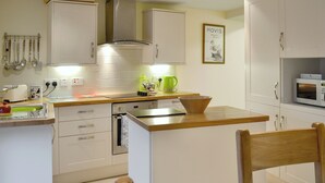 A modern kitchen with white cabinetry, a stainless steel range hood, and a green kettle on the countertop. - 3 bedroom accommodation in Seahouses (Seahouses)