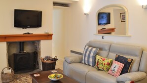 A living room with a sofa, a coffee table, a fireplace, a television, and a mirror. - 3 bedroom accommodation in Seahouses (Seahouses)