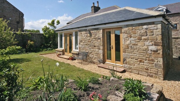A stone house with a garden, a small patio, and a clear sky. - 3 bedroom accommodation in Seahouses (Seahouses)