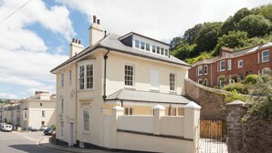 A two-story building with a beige facade, a stone wall, and a gated entrance. - 5 bedroom accommodation in Victoria Road (Victoria Road)