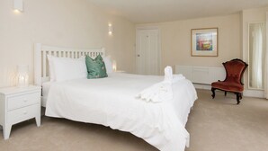 A bedroom with a large bed, a nightstand, a chair, a framed picture on the wall, and a door. - 5 bedroom accommodation in Victoria Road (Victoria Road)
