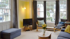 A living room with a sofa, a chair, a coffee table, and a TV. - 5 bedroom accommodation in Victoria Road (Victoria Road)