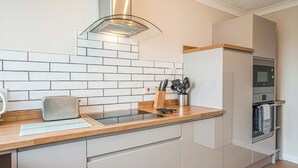 Eine moderne Küche mit Holzarbeitsplatte, Edelstahlgeräten und einer gefliesten Spritzschutzwand.