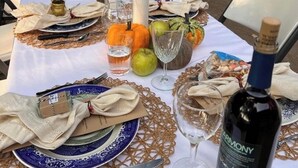 An outdoor dining setup with a table set for a meal, including plates, cutlery, and a bottle of wine. - Federalist style home close to down town minutes from the Field of Dreams! (Dyersville)