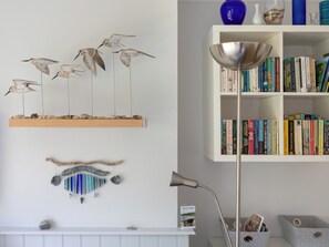A room with a white fireplace, a bookshelf with books, decorative wall art, and a floor lamp. - 3 bedroom accommodation in Salcombe (Salcombe)