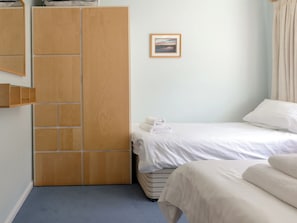 A bedroom with a bed, a wardrobe, and a framed picture on the wall.