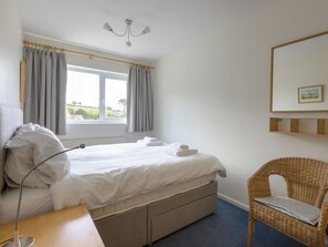 A bedroom with a bed, a bedside table, a lamp, a chair, a window with curtains, and a picture on the wall. - 3 bedroom accommodation in Salcombe (Salcombe)