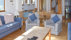 A living room with a sofa, two striped armchairs, a coffee table, and a dining area with a table and chairs. - 2 bedroom accommodation in Fore St (Fore St)