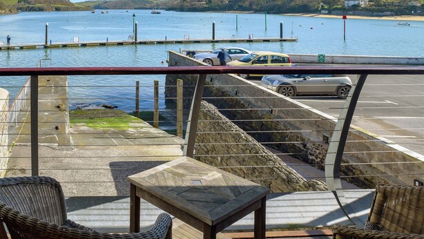 A waterfront view with a dock, boats, and a parking area with cars. - 2 bedroom accommodation in Fore St (Fore St)