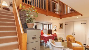 A staircase leading to a loft, a dining area with a red and white tablecloth, wicker furniture, and a potted plant. - 3 bedroom accommodation in Shadycombe Road (Shadycombe Road)