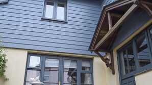 A building with a blue exterior, a window with a white curtain, and a table with chairs. - 3 bedroom accommodation in Shadycombe Road (Shadycombe Road)